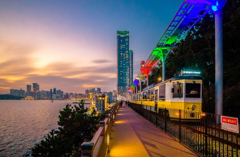 Beach Train and illuminated elevated track beside the coastal path at dusk