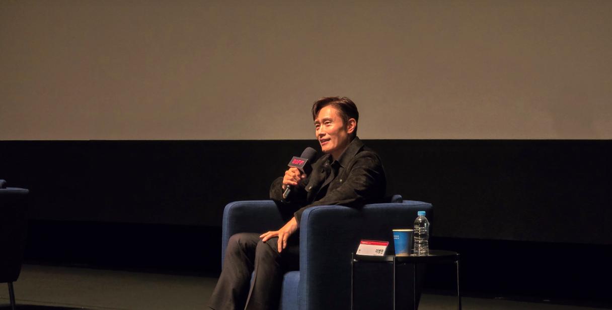 A seated guest speaking into a microphone at a film event