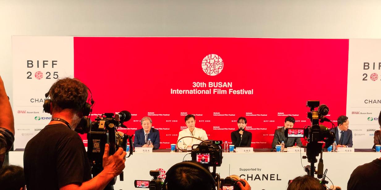 Press photographers facing a panel in front of a 30th BIFF 2025 backdrop