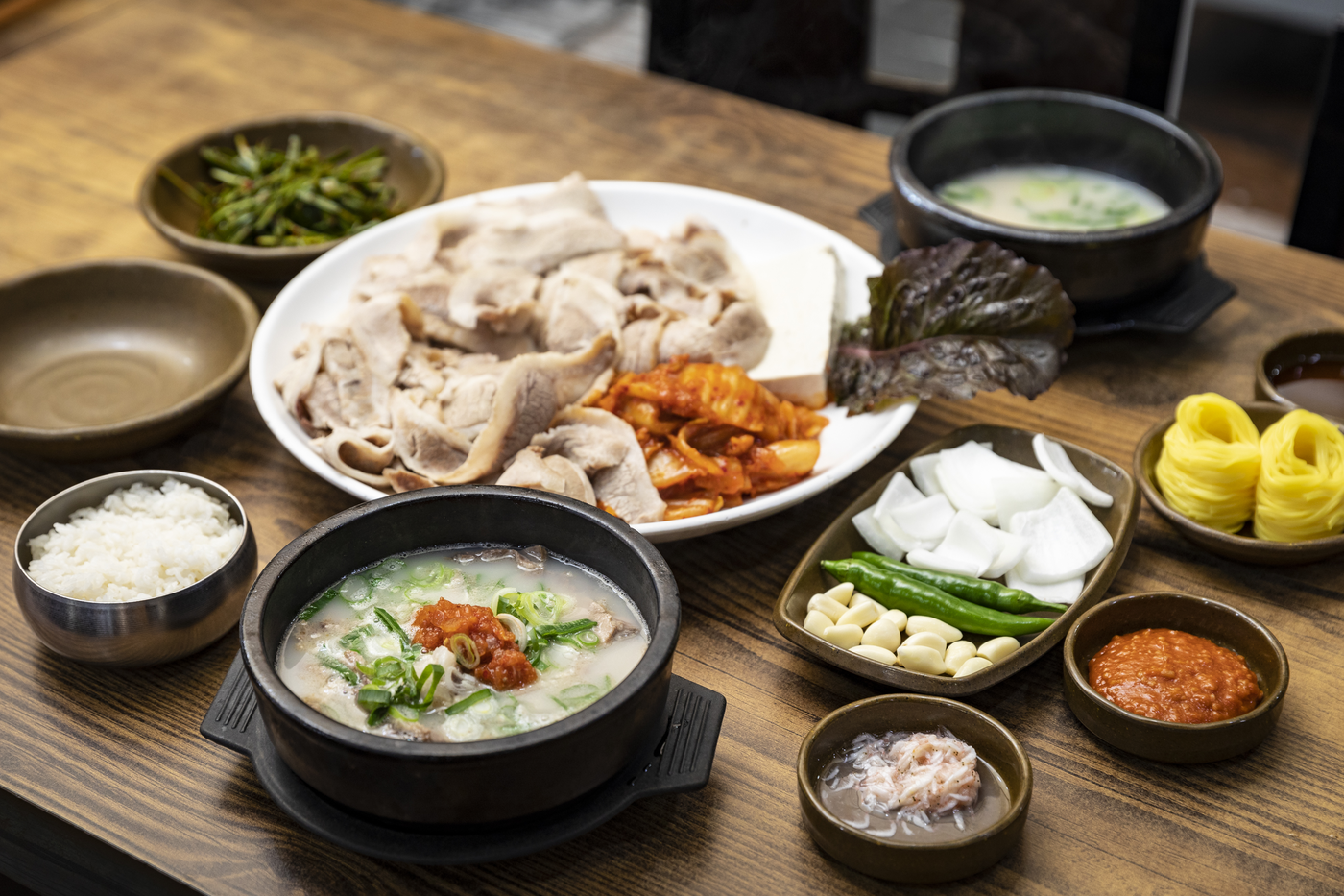 Pork soup, sliced pork and Korean side dishes on a table