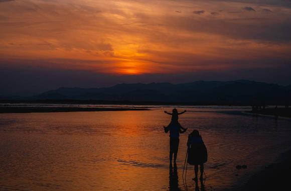 Visitors silhouetted against the orange sunset at Dadaepo Beach
