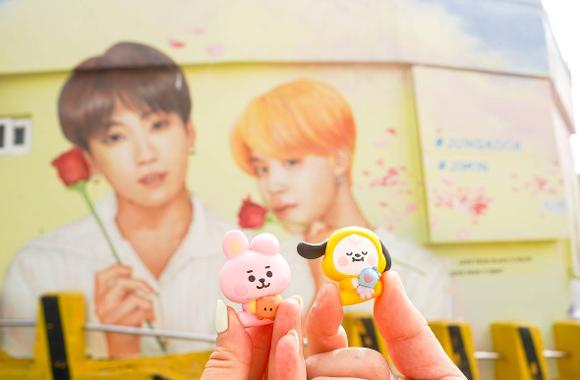 Fan figurines held in front of the Jimin and Jungkook mural in Gamcheon