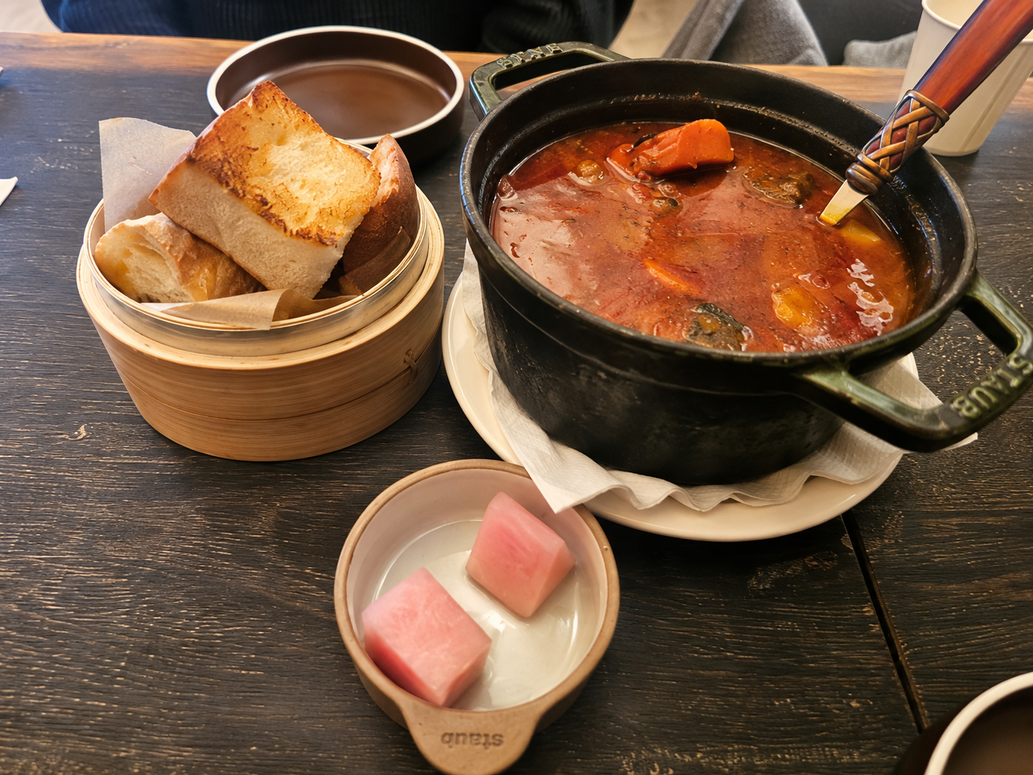 Stew with bread and pink pickles at Or — AI-assisted edit