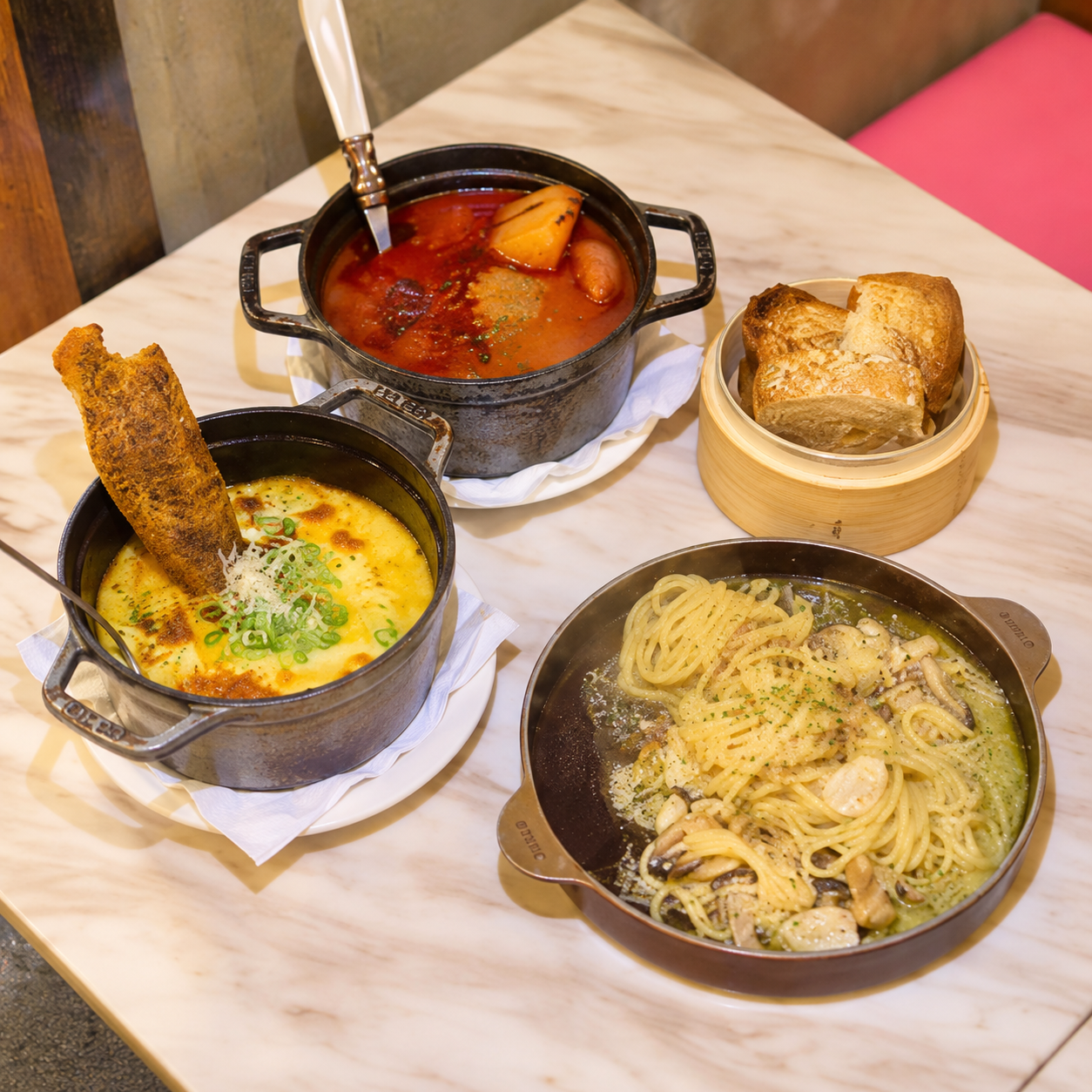 Two stew pots, pasta and bread on a table at Or — AI-assisted edit