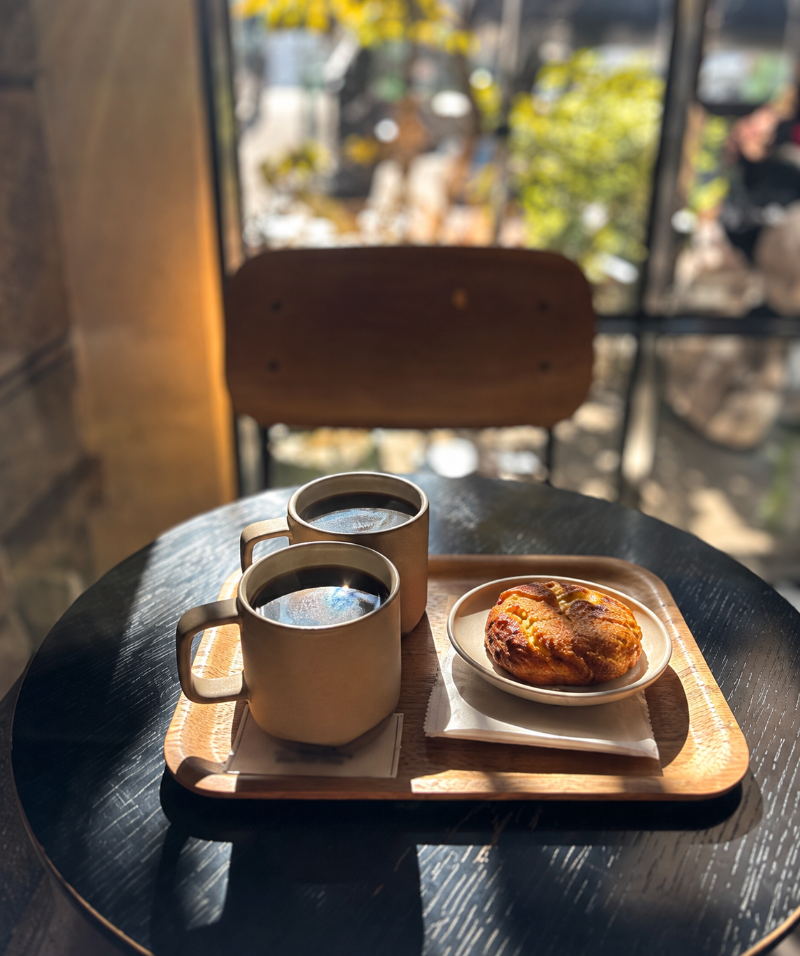 Two coffees and a pastry on a wooden tray at Strut Coffee — AI-assisted edit