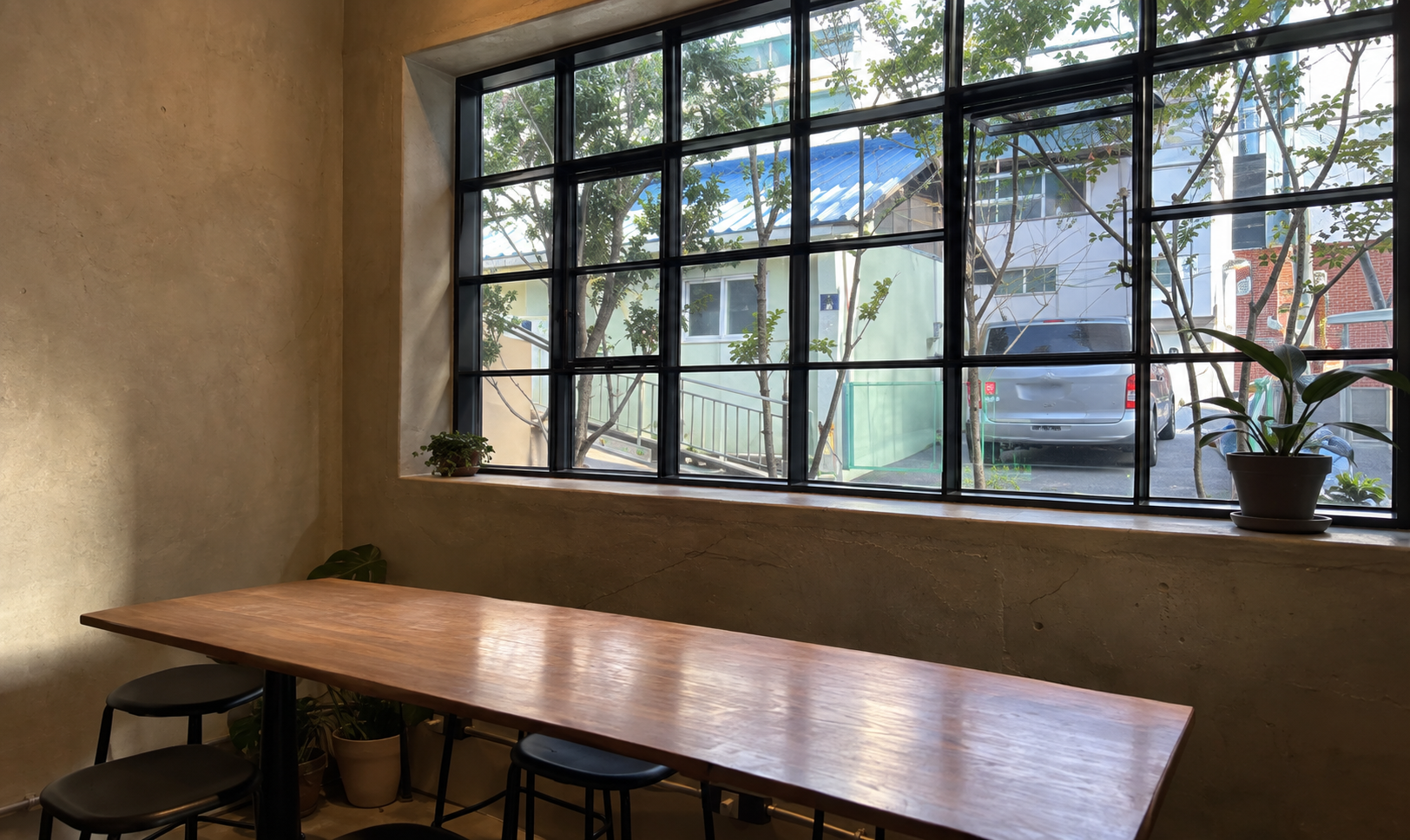 Wooden table beneath large windows at Strut Coffee — AI-assisted edit