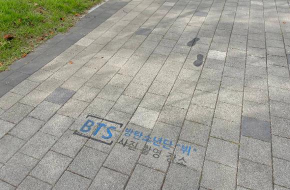 A pavement marker identifying V’s photograph location at Busan Citizens Park