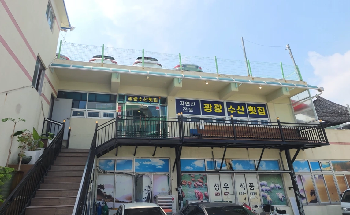 A second-floor raw-fish restaurant with yellow Korean lettering and an exterior staircase.