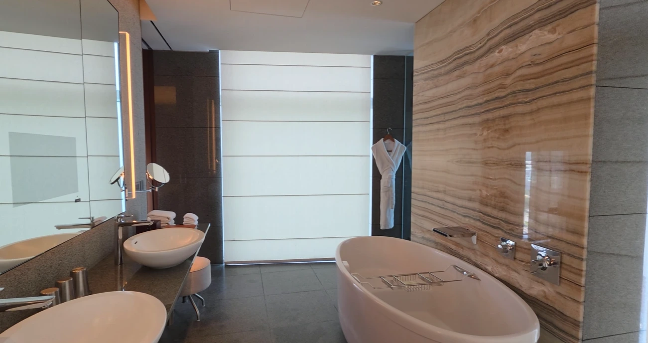 A bathroom with a freestanding bathtub, two basin sinks and a bathrobe at Park Hyatt Busan.