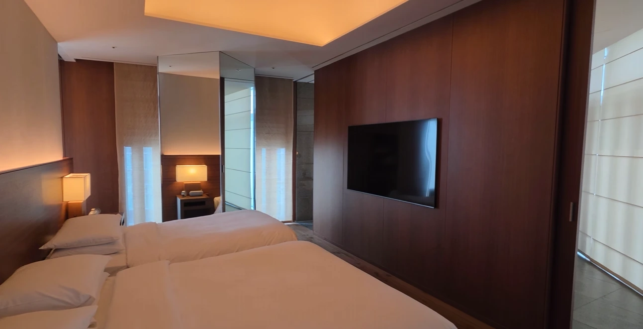 Two single beds beside a wood-paneled wall and television in a Park Hyatt Busan room.